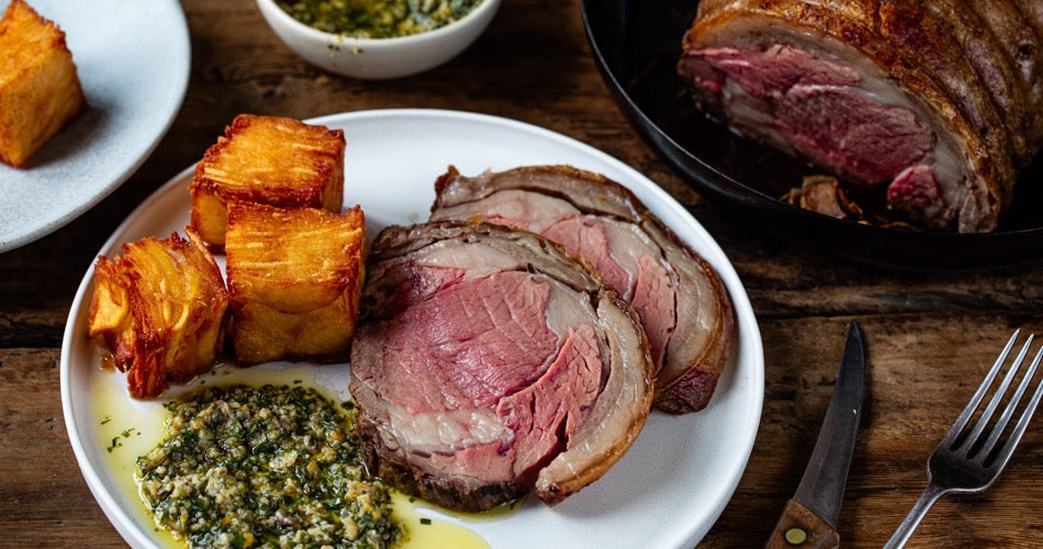 Sliced roast ribeye beef with crisp confit potatoes and green herb sauce
