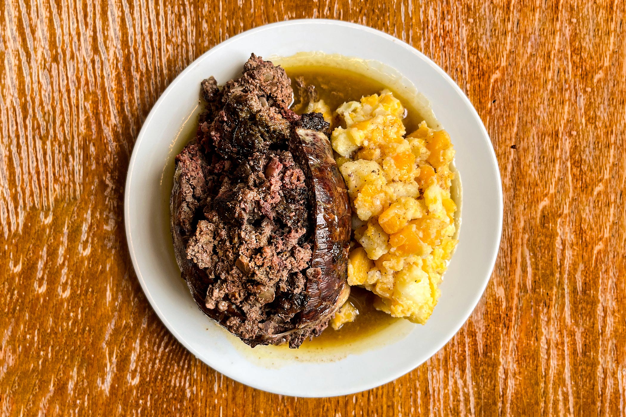 cooked st. john haggis served with neeps, tatties and braising juices spooned over