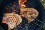 two pork loin chops cooking beautifully on the bbq and about to be served