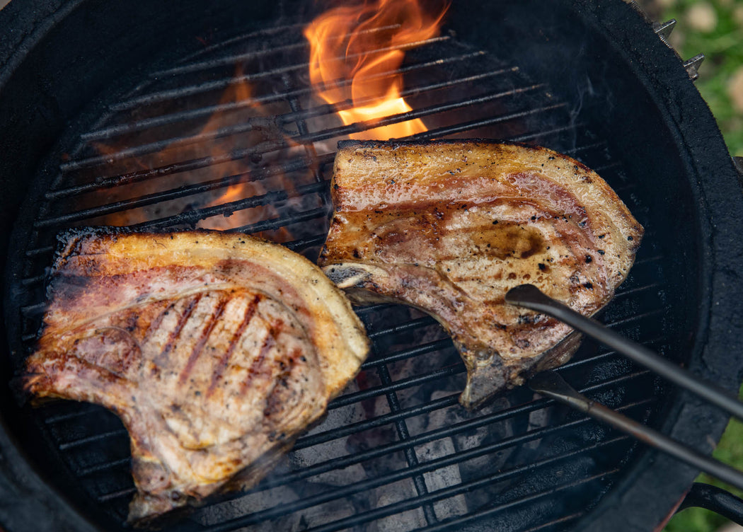 two pork loin chops cooking beautifully on the bbq and about to be served