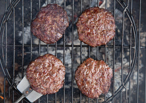 dry-aged, grass-fed steak burgers cooking on the bbq