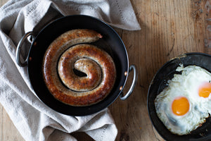 500g coiled cumberland sausage made to an ancient recipe with 81% coarsely minced pork slow baked in a cast iron frying pan and ready to be served for breakfast with fried eggs with runny yolks