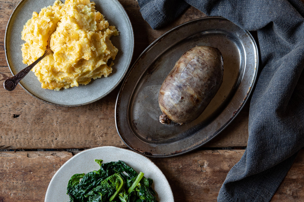 cooked haggis served with neeps, tatties and collard greens